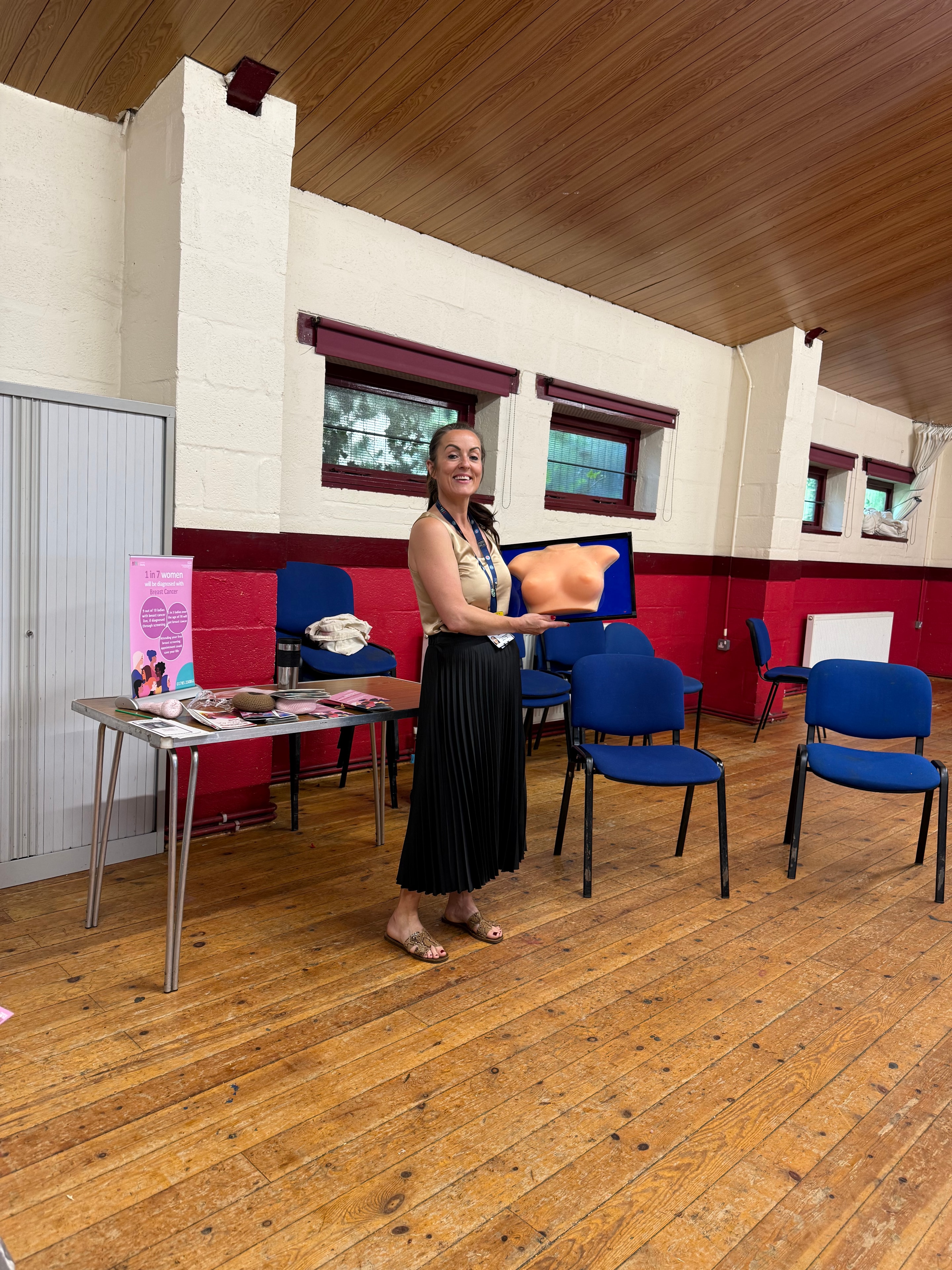 Community health event host standing beside information materials in a hall
